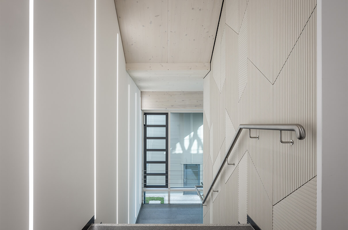 Helles freundliches Treppenhaus der Hammerbacher GmbH mit elegantem Lichtkonzept in Form von Lichtstreifen an den Wänden.